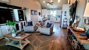 A spacious living room with a large TV, wicker furniture, and a wooden coffee table.