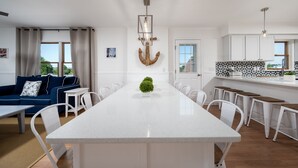 A modern kitchen with a central island, white cabinetry, and a hanging light fixture. - Amazing location and layout for vacation fun! 206 Massachusetts (Lewes)
