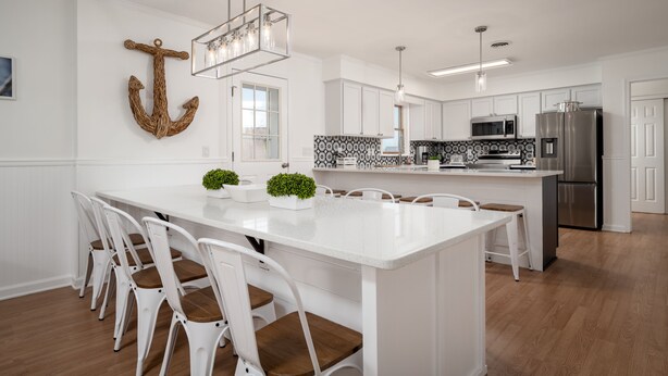 A modern kitchen with white cabinetry, a large island with seating, and a hanging light fixture. - Amazing location and layout for vacation fun! 206 Massachusetts (Lewes)