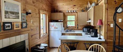 Ein Interieur einer Holzhütte mit Küche, Essbereich und Kamin.