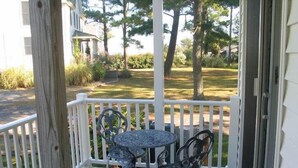 A wooden porch with a round table and two chairs.