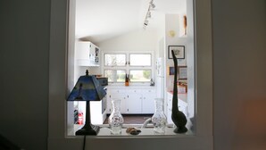 A kitchen with white cabinets, a window, and a lamp.