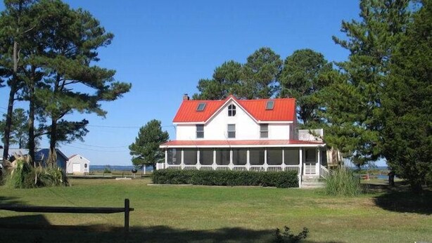 A two-story house with a red roof and a covered porch.
