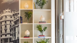 A modern interior with a bookshelf, a 'SALIDA' sign, and a mural of a building.