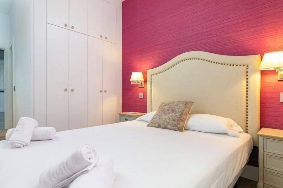Een hotelkamer met een bed, nachtkastje, lamp en kledingkast.