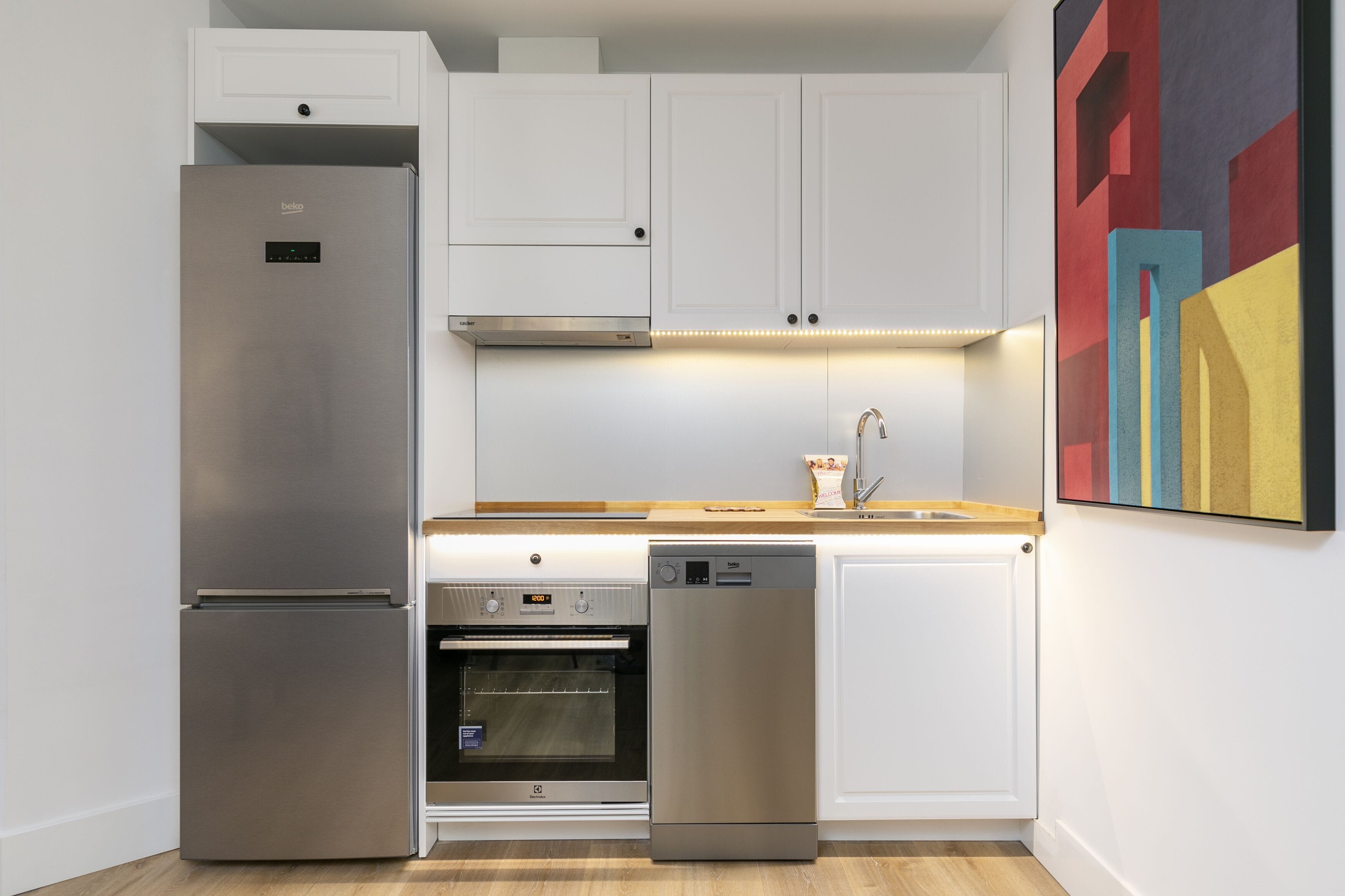 Una cocina moderna con armarios blancos, electrodomésticos de acero inoxidable y un horno empotrado.