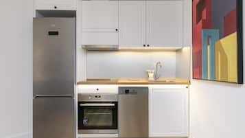 Una cocina moderna con armarios blancos, electrodomésticos de acero inoxidable y un horno empotrado.