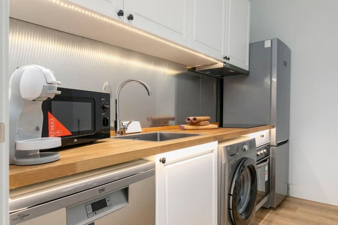 A compact kitchen with a microwave, sink, dishwasher, and washing machine.