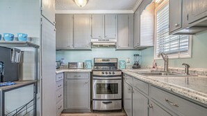 A compact kitchen with grey cabinets, a stainless steel oven, and a granite countertop. - Please welcome "Two Hands Excited" to the Ocean Lakes rental program. (Myrtle Beach)