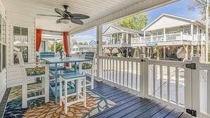 A covered porch with a table and chairs, a ceiling fan, and a view of neighboring buildings. - Please welcome "Two Hands Excited" to the Ocean Lakes rental program. (Myrtle Beach)