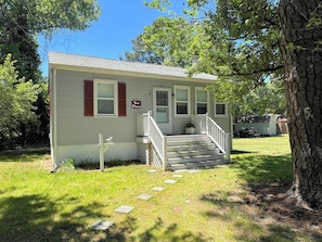 A small, single-story house with a front porch, a mailbox, and a 'Sea Pines' sign.