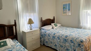 A bedroom with two beds, a nightstand, a lamp, and a painting on the wall. - Sea Pines -2BR  CLOSE TO SHOPPING,SCREENED PORCH, Linens and Towels Provided (Chincoteague)