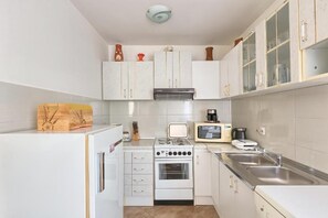 Una cocina compacta con armarios blancos, estufa, microondas y lavaplatos.