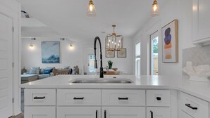 Una cocina moderna con armarios blancos, una isla central e iluminación colgante.