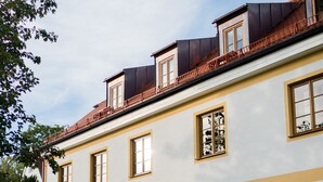 A multi-story building with a white facade and yellow trim, featuring multiple windows and a visible sign that reads "Peterhof." - Bob W Munich Airport - Peterhof (Freising)