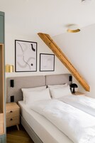 Un dormitorio con cama, mesitas de noche y dos obras de arte abstractas enmarcadas en la pared.