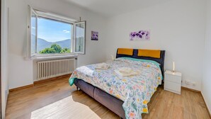 A bedroom with a bed, a nightstand, a window, and a radiator. - Ca' Gina Panoramica - Monte Bre (Lugano)