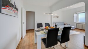 A modern living room with a dining area, a sofa, and a painting on the wall. - Ca' Gina Panoramica - Monte Bre (Lugano)