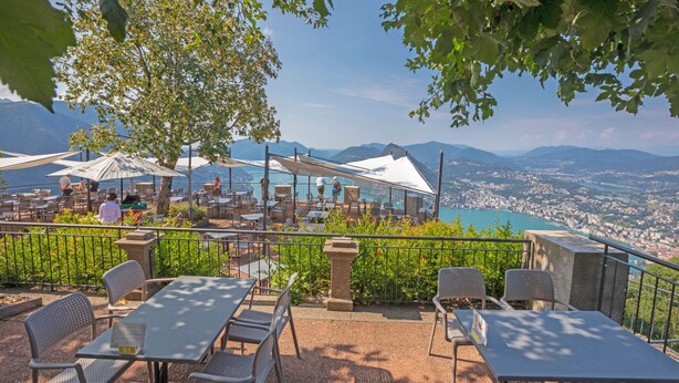 An outdoor terrace with tables and chairs, overlooking a city and mountains. - Ca' Gina Panoramica - Monte Bre (Lugano)