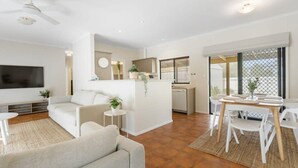Una sala de estar moderna con un sofá, televisor y un comedor con sillas y una mesa.