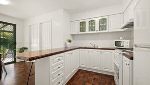A kitchen with white cabinets, a wooden countertop, a microwave, and a refrigerator. - The Black Door Bright, Victoria (Bright)