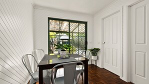 A dining area with a table, chairs, and a view through a window. - The Black Door Bright, Victoria (Bright)