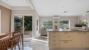 Una cocina moderna con una isla grande, una zona de comedor con muebles de madera y vistas al jardín a través de puertas de cristal.