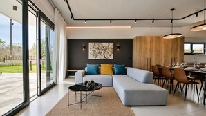 Un salon moderne comprenant un canapé d’angle, un coin repas et une grande fenêtre donnant sur l’extérieur.
