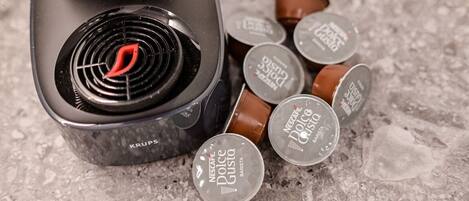 A coffee machine with a Krups brand label and Nescafe Dolce Gusto coffee pods on a textured surface.