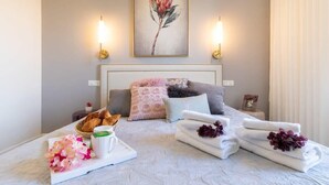 A hotel room with a bed, bedside lamps, a painting, and a breakfast tray with flowers. - King David Luxury 2BR/Parking/View Old City (Jerusalem)