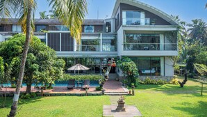 A modern two-story house with a pool, surrounded by lush greenery and palm trees. - Amã Stays & Trails Sherly'S Ente Kumbalanghi, Kochi (Kochi)