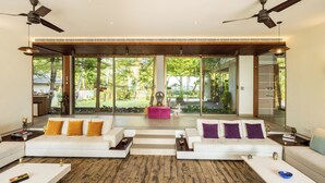 A spacious living area with two white sofas, a wooden floor, and large glass doors leading to a garden. - Amã Stays & Trails Sherly'S Ente Kumbalanghi, Kochi (Kochi)