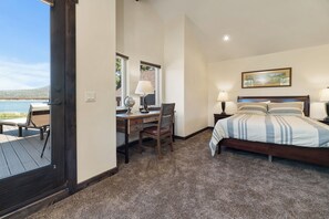 Une chambre avec un lit, un bureau et une chaise, une fenêtre donnant sur la plage et un tableau accroché au mur.