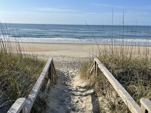 A wooden boardwalk leading to a sandy beach with ocean views.