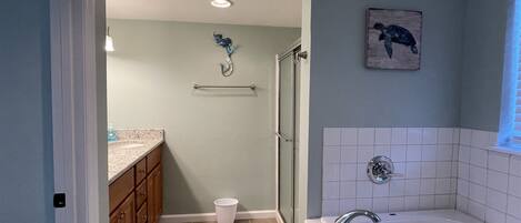 Une salle de bain équipée d’une douche, d’une baignoire, d’un porte-serviettes et de toilettes.