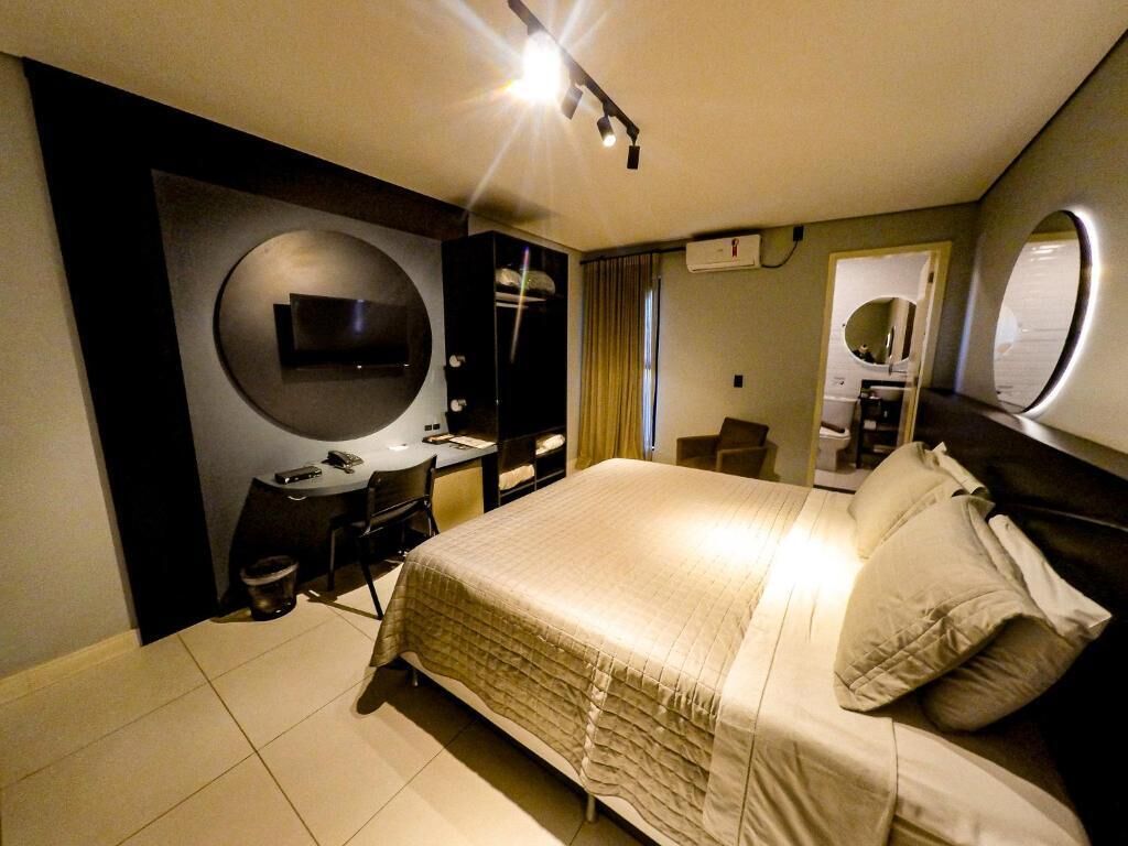 Habitació d'hotel moderna amb llit, escriptori, cadira, televisió i finestra.