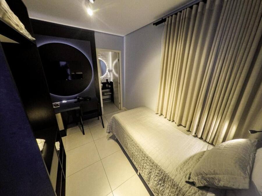 A compact hotel room with a bed, a desk, and a television.