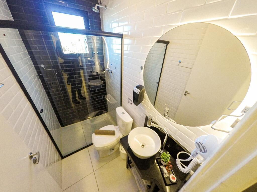 Un bagno moderno con doccia vetrata, un water bianco, un lavandino con specchio e un asciugacapelli.