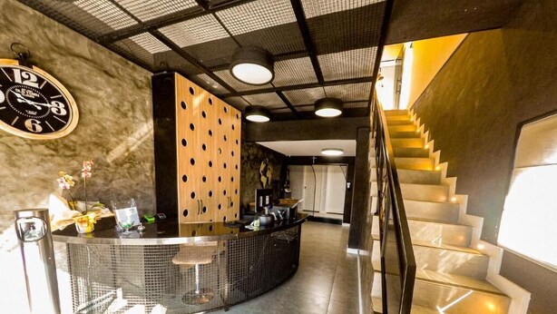 A modern hotel lobby with a reception desk, a staircase, and a clock on the wall. - Castro's Hotel (Telemaco Borba)