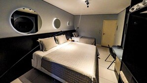 A modern bedroom with a large bed, a desk, and a TV. There are circular wall decorations and a door in the room. - Castro's Hotel (Telemaco Borba)