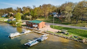 A lakeside property with a dock, a small building, and a grassy area. - Lakefront Cottage with Hot Tub & Fire Pit (Fife Lake)