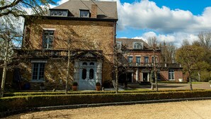 A stone building with a prominent entrance, large windows, and a tiled roof. - Domaine Du Vivier L'Agneau (Assesse)