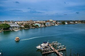 A marina with boats docked, a thatched boat in motion, and buildings in the background.