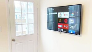 Un televisor de pantalla plana montado en la pared, con una ventana a la izquierda.