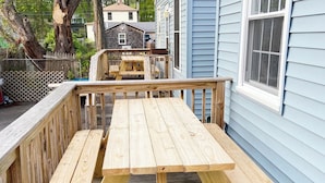 Una terraza de madera con una mesa de picnic, rodeada por barandilla de madera.