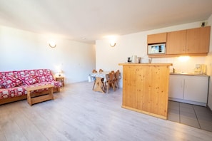 A compact living space with a sofa, a dining table, and a kitchenette area.