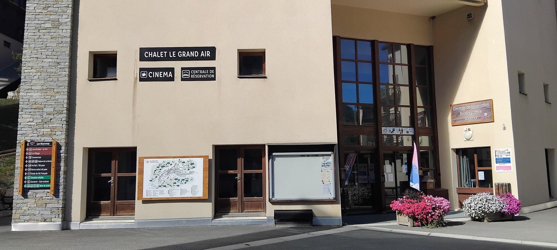 A building with a sign for 'Chalet Le Grand Air' and 'Centrale de Reservation' indicating a cinema and reservation office.
