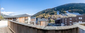 A mountainous town with buildings, including a wooden structure and a modern building with balconies. - 160m from ski slopes, 1st floor, balcony, parking, tv, ski locker, 25m², La Norma (La Norma)