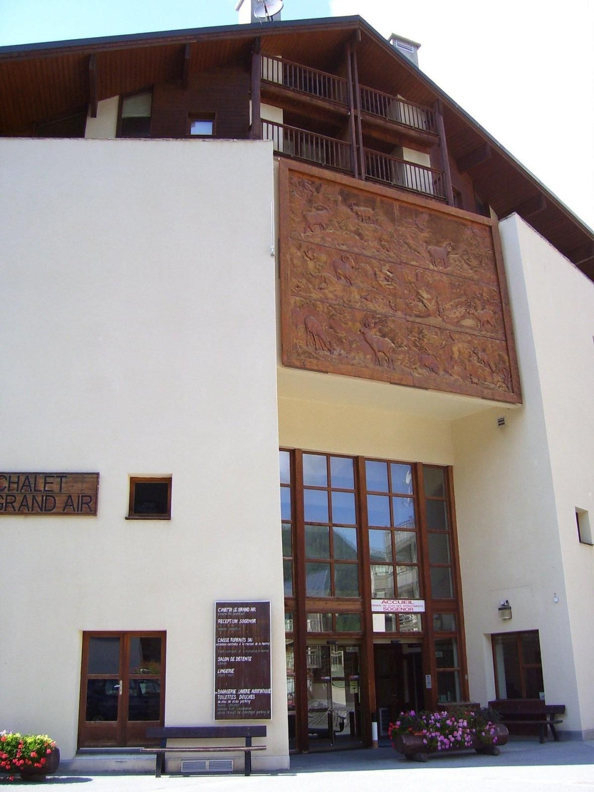 A building with a sign reading "CHALET GRAND AIR" and a large wooden panel with animal carvings.