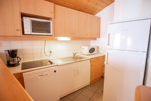 A compact kitchen with a Bosch dishwasher, a microwave, and a refrigerator.